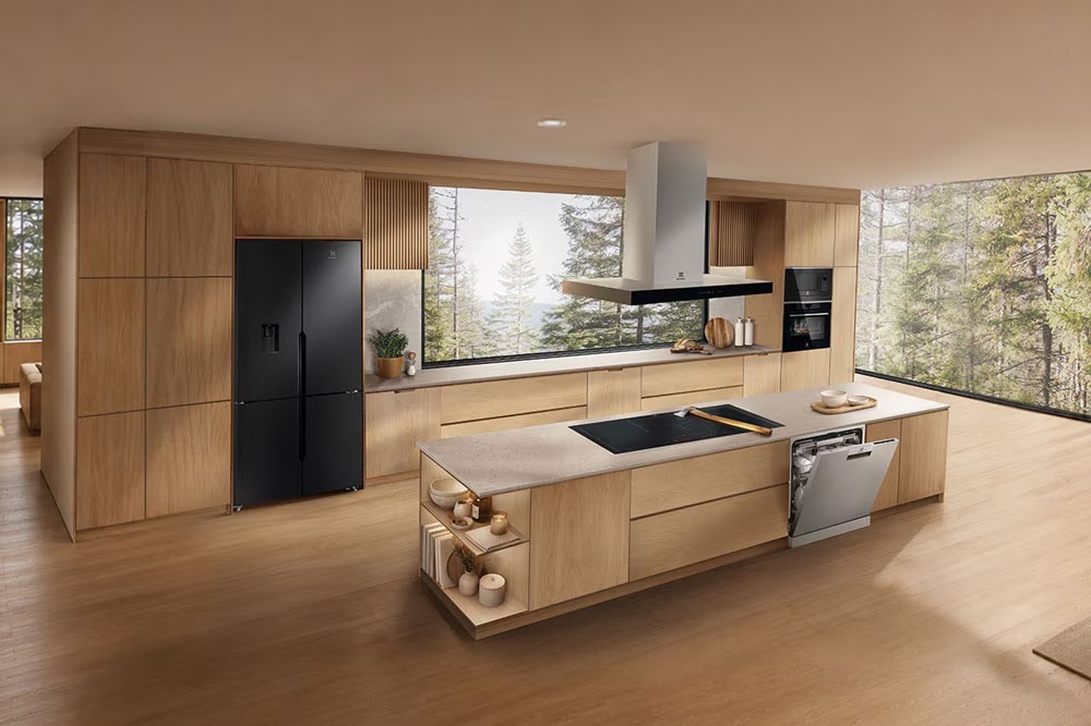 Tủ lạnh side-by-side màu đen, máy hút mùi, bếp từ và máy rửa bát trong căn bếp gỗ hiện đại