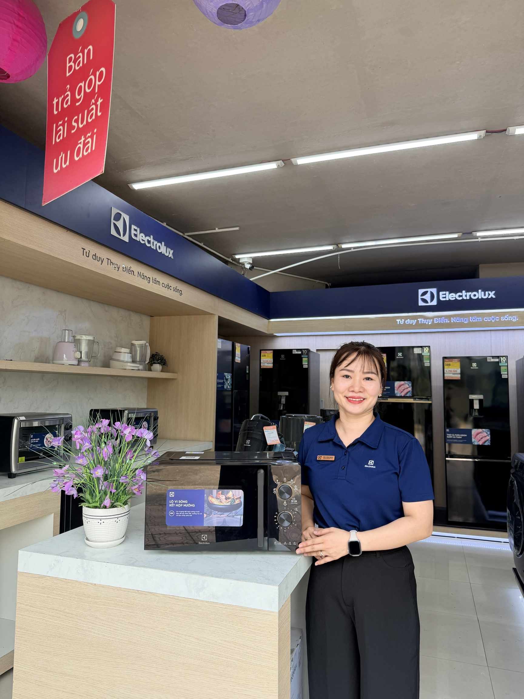 Lò vi sóng Electrolux kết hợp nướng màu đen trưng bày tại cửa hàng điện máy, nhân viên đứng bên cạnh